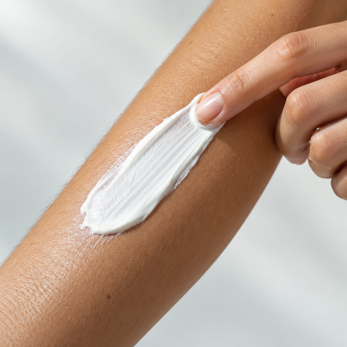 Sunscreen agents: a white sunscreen streak being applied to a forearm.